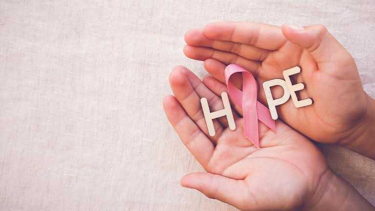 Pink ribbon and hope word in woman’s hands symbolising cancer awareness and mental health support.
