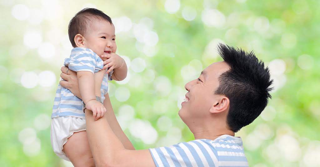 Father’s Day and Loneliness Awareness Month – Hong Kong father holding up his smiling baby.