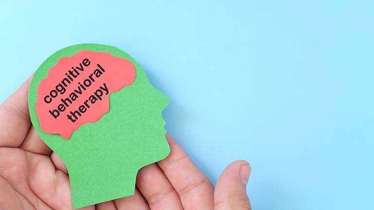 Hands holding green human head profile with the words “Cognitive Behavioural Therapy” for mental health benefits