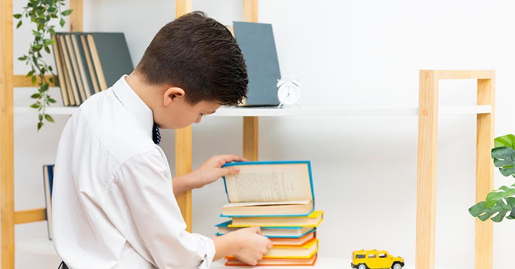 An image of a young boy searching for something amidst a pile of books.